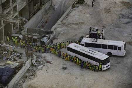 Immigrant workers line up to board the bus back to their compound after a days work